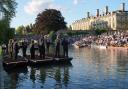 People sit on the banks of the River Cam and lawns of King’s College in Cambridge, as they listen to The King’s Men perform (Joe Giddens/PA)