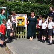 Grove Primary School head Rachel Kounnas (light green dress) watches Jayne Biggs remove the ribbon at the unveiling of the public access defibrillator. Picture: Mick Howes