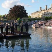 People sit on the banks of the River Cam and lawns of King’s College in Cambridge, as they listen to The King’s Men perform (Joe Giddens/PA)